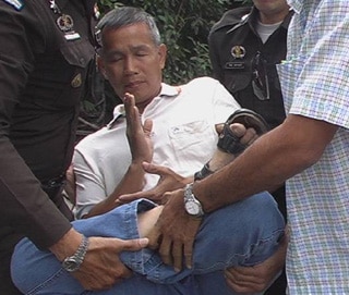 A practitioner of Falun Gong is carried away by uniformed and plain-clothes police in Bangkok. Practitioners were meditating in quiet protest across the street from the Chinese embassy.