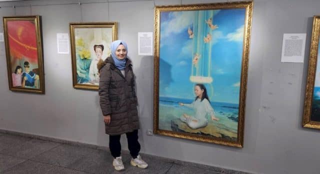 Altun Bulut stands next to painting at the Zhen Shan Ren International Art Exhibition in Istanbul, Turkey. “When I looked at the paintings, I saw that the souls were suffering. However, they contained more than just pain, they showed truth.”