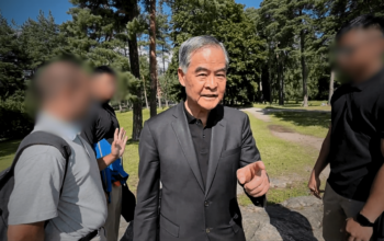 Leung Chun-ying (center) approaches and verbally confronts a Falun Gong practitioner in a public park in Finland.