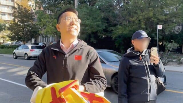 A Mandarin-speaking man threatens to kill a Falun Gong practitioner outside the Chinese consulate in Toronto as he tears apart the practitioner’s banners. (Nora Geng)