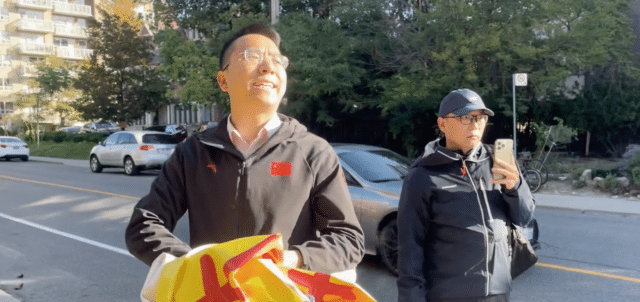 A Mandarin-speaking man threatens to kill a Falun Gong practitioner outside the Chinese consulate in Toronto as he tears apart the practitioner’s banners. (Geng)